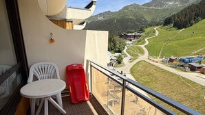 A balcony with a table and chairs, overlooking a mountainous landscape with a ski lift and buildings. - 3-room apartment at the foot of the slopes, 7th floor (Les Adrets-Prapoutel)