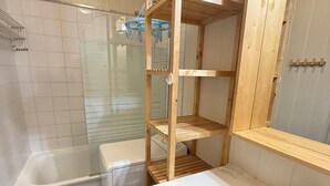 A bathroom with a white sink, a mirror, and a wooden shelf unit. - 3-room apartment at the foot of the slopes, 7th floor (Les Adrets-Prapoutel)