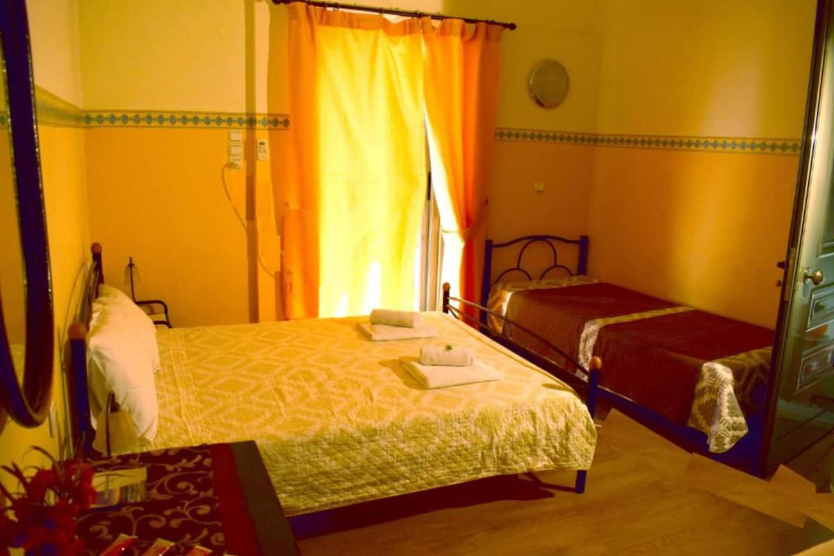 Une chambre d’hôtel avec deux lits, un bureau, une chaise et un miroir.