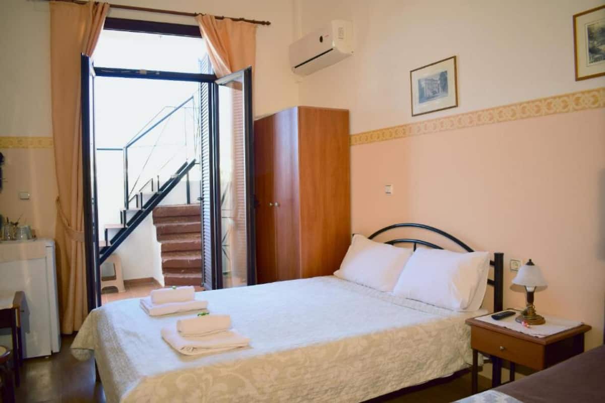 Une chambre d’hôtel comprenant un lit, une table de chevet, un bureau, une armoire et un escalier menant à un espace extérieur.