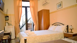 Quarto de hotel com cama, escrivaninha, cadeira, armário e escada.