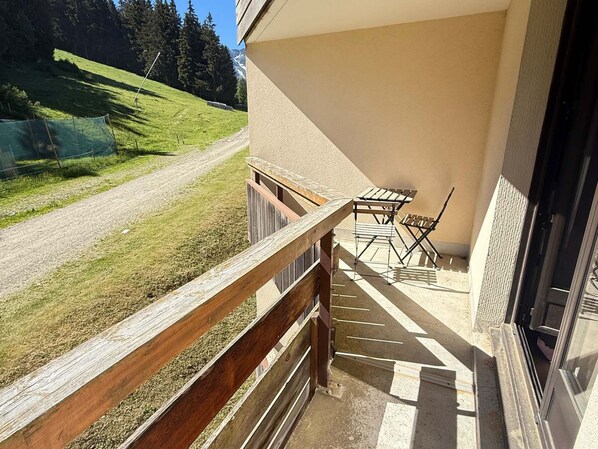 A balcony with a wooden railing, a table, and two chairs.