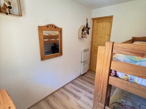 A room with a bunk bed, a wooden mirror, a heater, and a door. - Cozy 2-room apartment at the foot of the slopes with balcony (Les Adrets-Prapoutel)