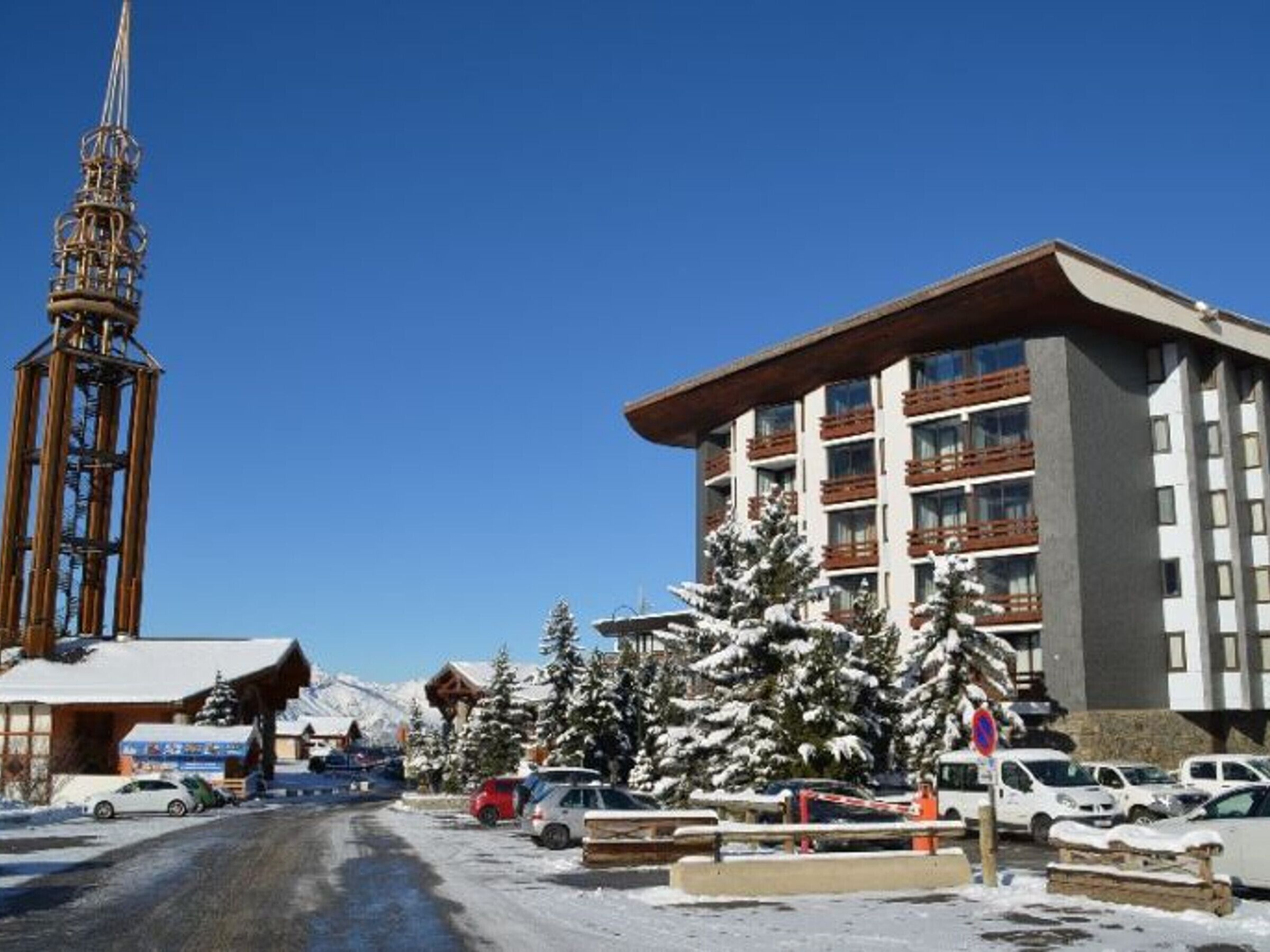 A hotel with a modern design, featuring multiple balconies and a ski lift tower in the background.
