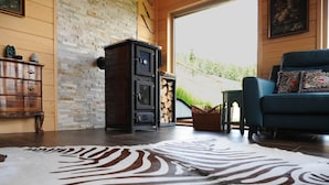Una habitación con pared de piedra, un armario de madera, un sofá azul y una alfombra con estampado de cebra.