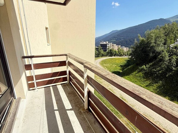 A balcony with a view of a mountainous landscape and a road.