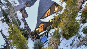 Ein mehrstöckiges Holzhaus mit einem markanten, mit Schnee bedeckten Dach und zahlreichen Fenstern.