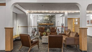 Un vestíbulo con pared de piedra, sillones de cuero, un banco de madera y una pequeña mesa con plantas.
