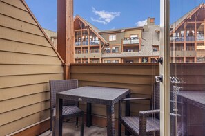 A balcony with wicker furniture and a view of multi-story buildings. - Sophisticated Mountain Condo – Pool & Hot Tub (Canmore)