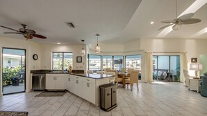 A spacious kitchen with a large island, dining area with chairs, and a view through glass doors. - Wide Water Views, Hot Tub, Heated pool! 75 reviews.Villa 27 (Cape Coral)