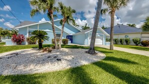 A residential house with a front yard, palm trees, and a driveway. - Wide Water Views, Hot Tub, Heated pool! 75 reviews.Villa 27 (Cape Coral)