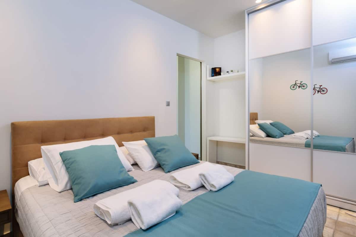 Ein Hotelzimmer mit einem großen Bett, zwei Kissen, einem Nachttisch, einem Spiegel und einem Regal mit einer Fahrrad-Dekoration.