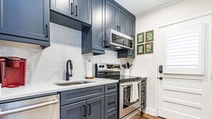 A kitchen with gray cabinets, a stainless steel refrigerator, a microwave, and a double oven. - Comfortable and Quiet Condo near the Village and NC State (Raleigh)