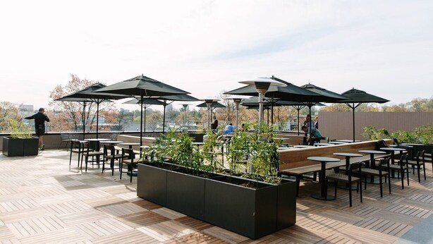 An outdoor seating area with tables and chairs, surrounded by planters and umbrellas. - Comfortable and Quiet Condo near the Village and NC State (Raleigh)