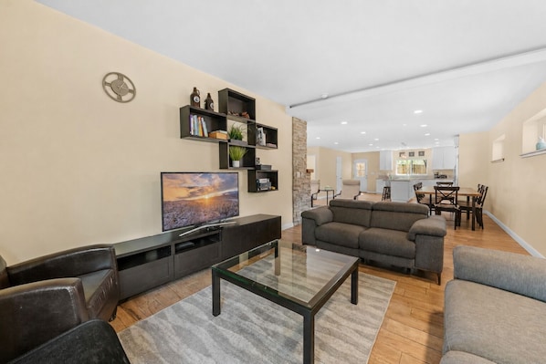 A modern living room with a flat-screen TV, a sectional sofa, and a glass coffee table.