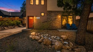 A two-story house with a stone facade, a front door, and a small porch with chairs. - Modern Times - Partial AC, Close to Lake & Village, Jet Tub, Fireplace, Barbecue (Big Bear Lake)