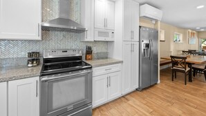 A modern kitchen with white cabinetry, stainless steel appliances, and a herringbone tile backsplash. - Modern Times - Partial AC, Close to Lake & Village, Jet Tub, Fireplace, Barbecue (Big Bear Lake)