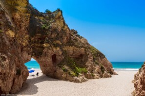 Dramatic natural rock arch on a golden sand beach near Lagos, showcasing the iconic Algarve coastline with its sculpted limestone cliffs and crystal-clear waters, easily accessible from Casa Vista Lago