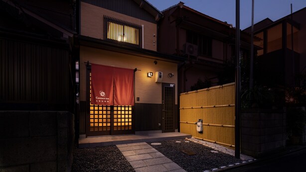 Ein traditionelles japanisches Gebäude mit hölzernem Tor, einem roten Banner und einem gut beleuchteten Eingang.