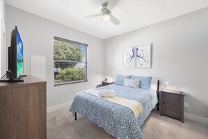 A bedroom with a bed, a TV, a window with blinds, a ceiling fan, and artwork on the wall. - Waterfront Home on Key Lot | Pool & Sundeck (Marco Island)