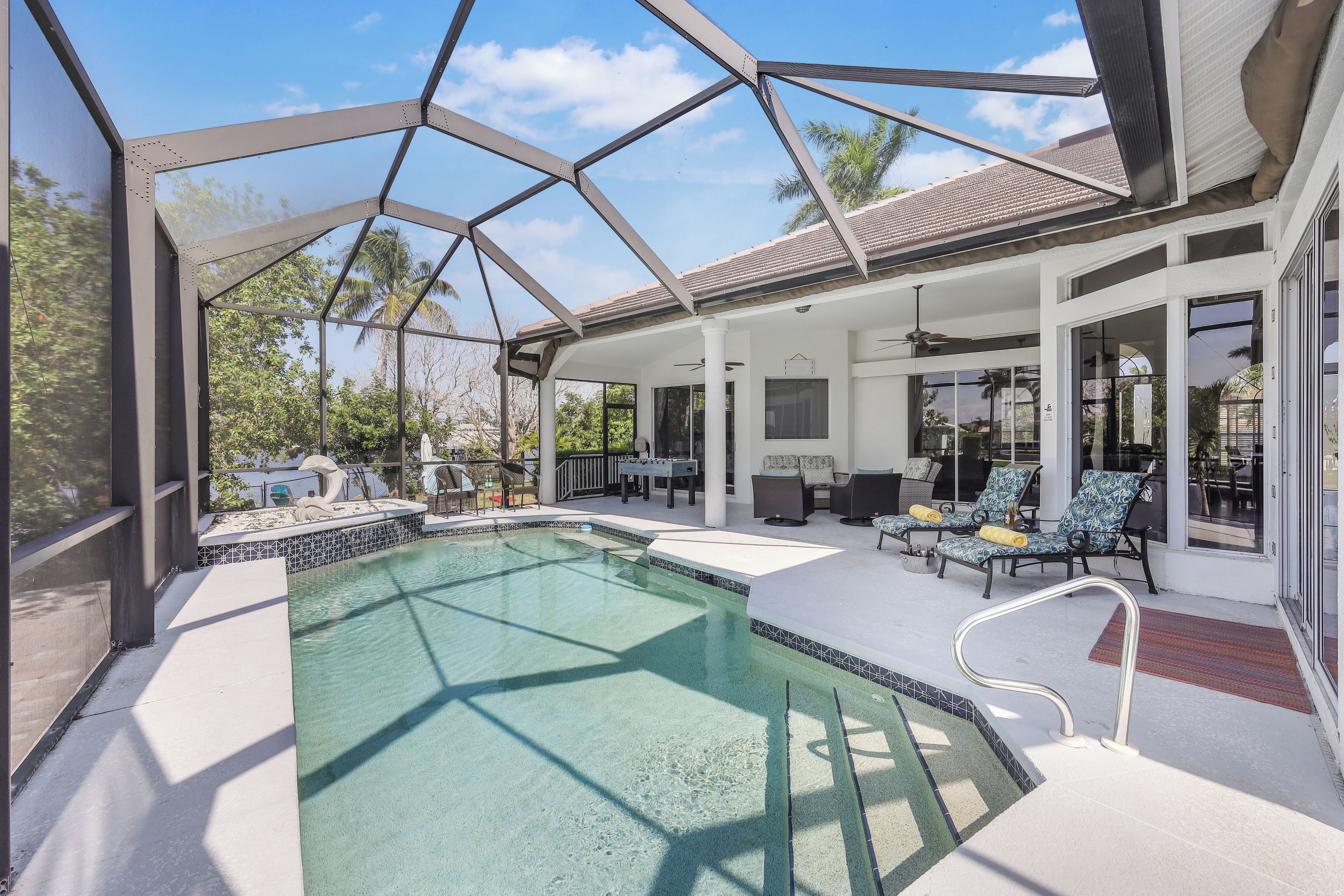 A pool area with a glass enclosure, outdoor seating, and a covered patio.