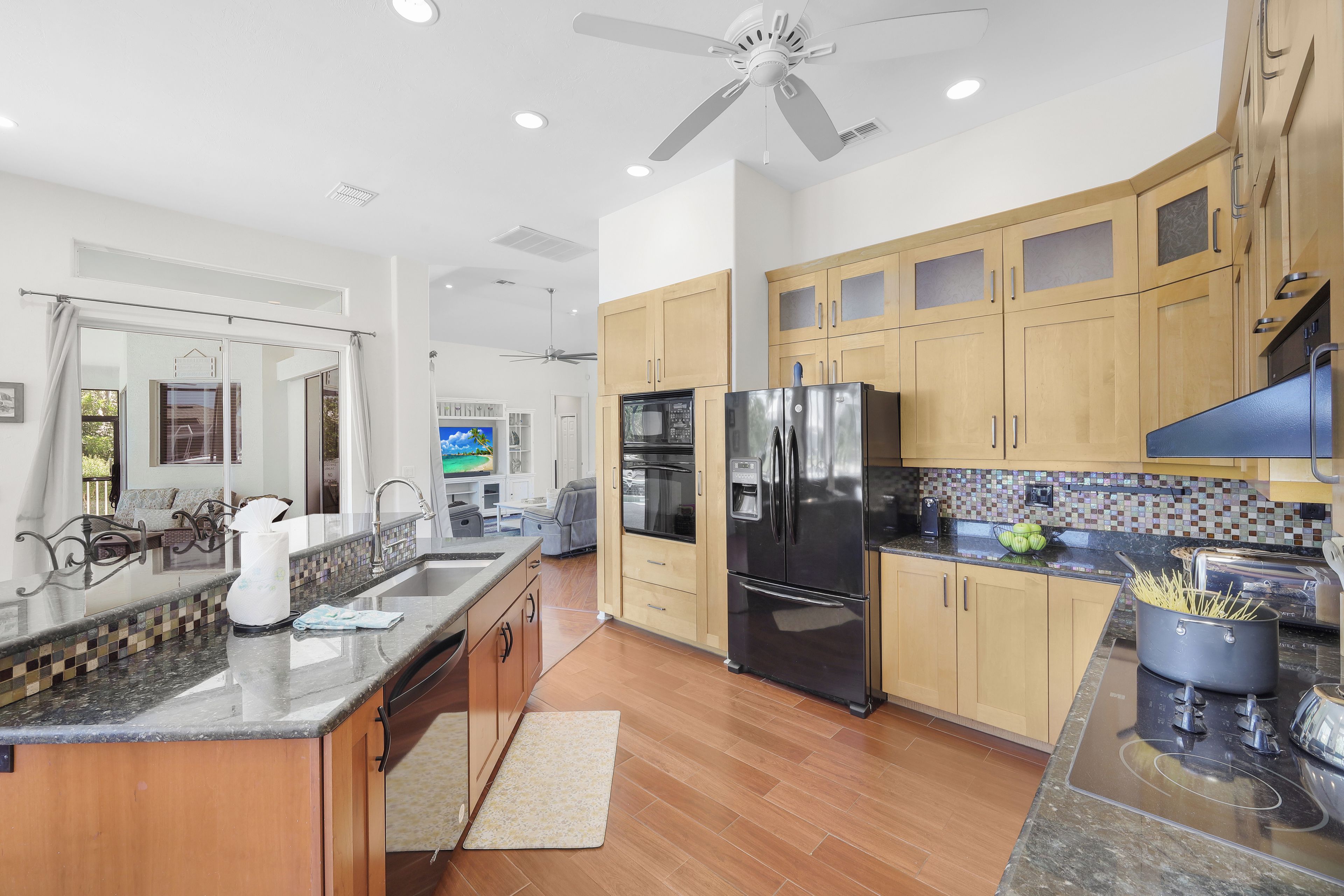A modern kitchen with wooden cabinets, a stainless steel refrigerator, and a granite countertop.
