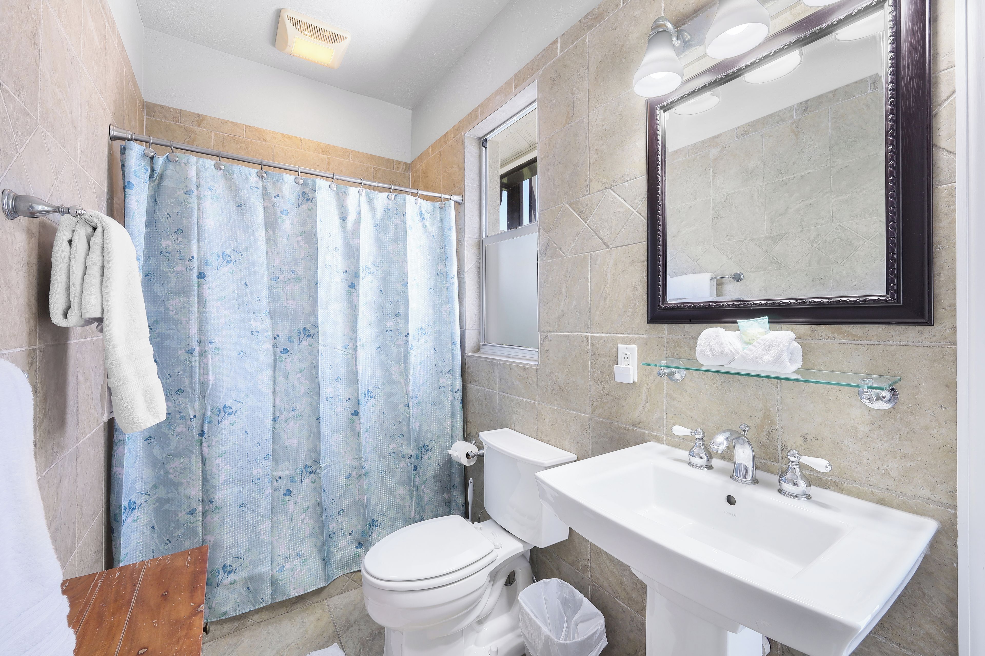 A bathroom with a toilet, sink, shower curtain, and a mirror.