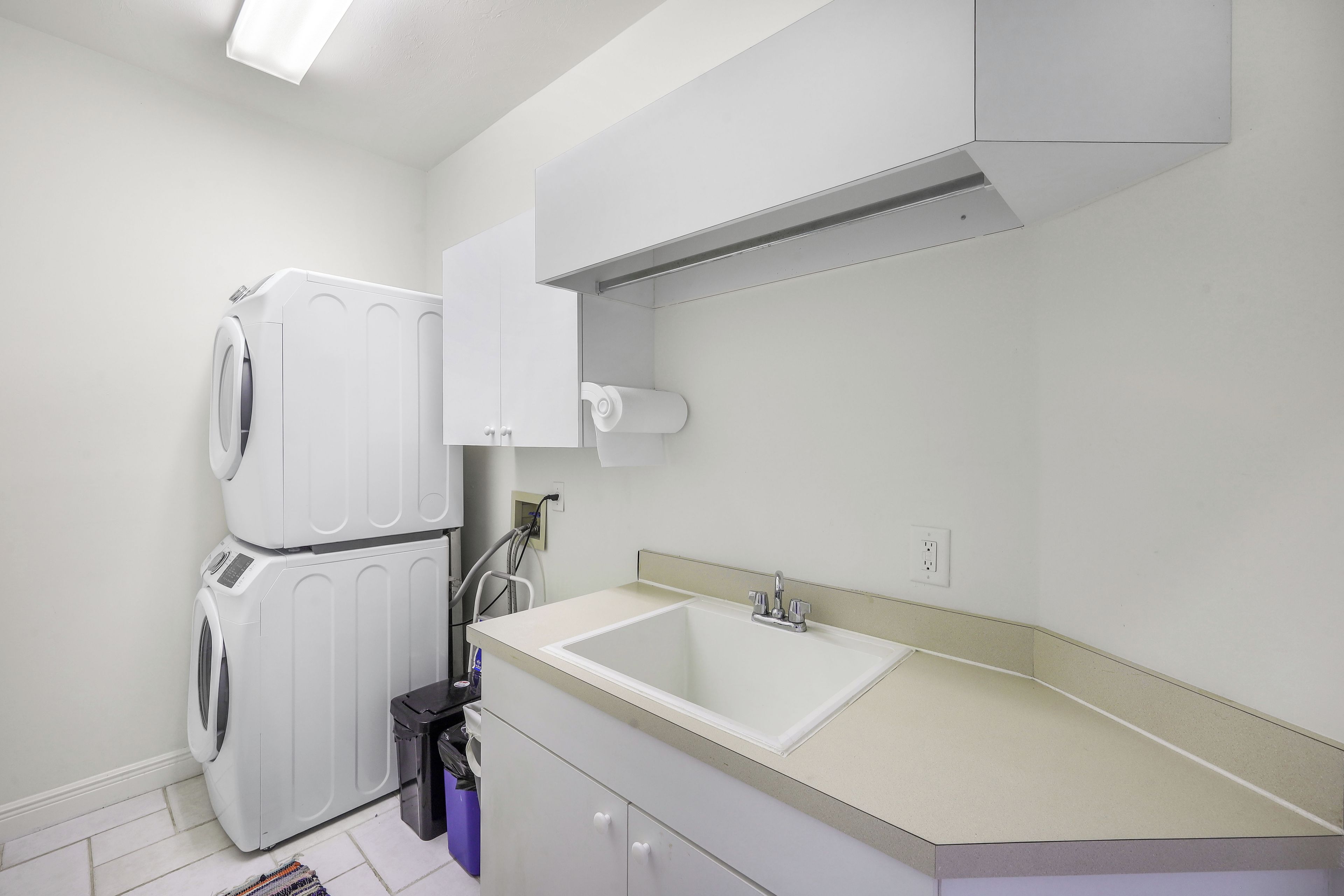 A compact kitchen with a built-in washing machine, a sink, and a small trash bin.