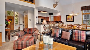 A spacious living room with a fireplace, a dining area with wooden chairs, and a kitchen with wooden cabinets. - Enclave #217 5 Bedroom Home by RedAwning (Avon)