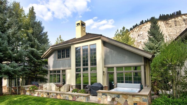 A two-story house with a stone foundation, large windows, and a hot tub in the backyard. - Enclave #217 5 Bedroom Home by RedAwning (Avon)