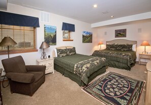 Ein Schlafzimmer mit zwei Betten, einem Sessel, einem Nachttisch und einer Kommode.