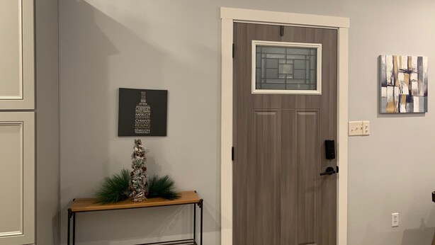 A hallway with a grey door, a small table with a decorative item, and a framed picture on the wall.
