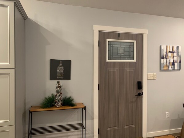 A hallway with a grey door, a small table with a decorative item, and a framed picture on the wall.