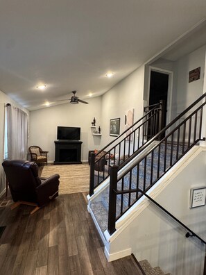 A living room with a fireplace, a television, a sofa, and a staircase.