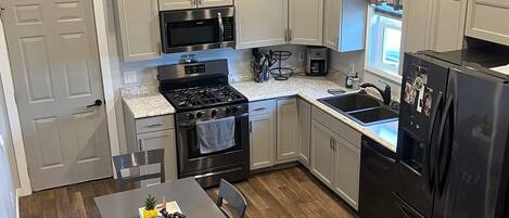 A modern kitchen with a central island, stainless steel appliances, and a dining area with a table and chairs.
