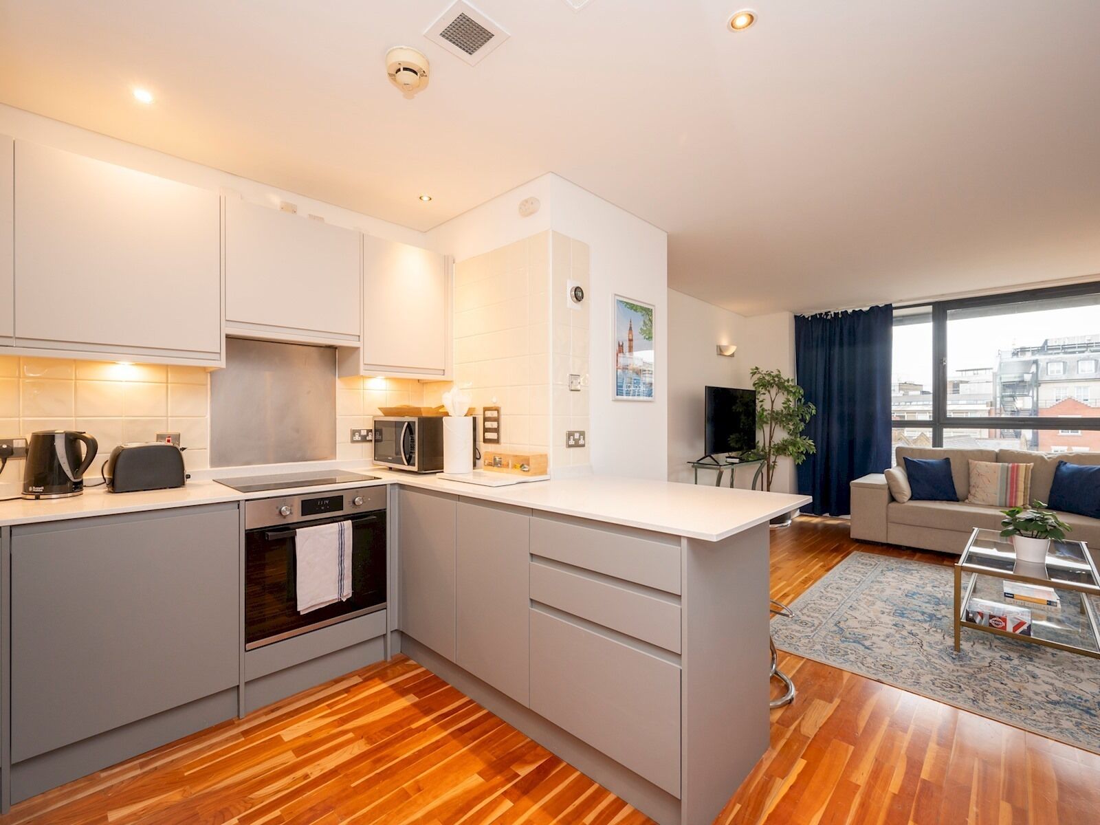 A modern apartment with a kitchen, living area, and a large window.