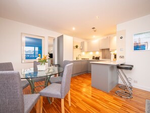 A modern apartment with a dining area, kitchen, and a view of the city.