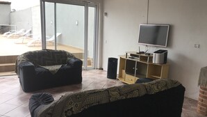 A living room with a sofa, a television, and a cabinet. - House on the south coast with optional heated pool. (Mongaguá)