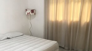 A room with a bed, a wall-mounted light, and a window with curtains. - House on the south coast with optional heated pool. (Mongaguá)