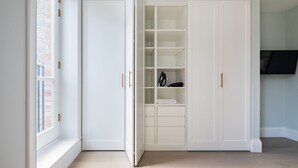 Una stanza con un ampio guardaroba bianco, una finestra e una TV a schermo piatto fissata al muro.