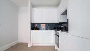 Una cucina moderna con mobili bianchi, un piano di lavoro nero e un forno in acciaio inossidabile.