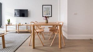 Un'area pranzo moderna con un tavolo e sedie in legno, una TV a schermo piatto montata sulla parete e un quadro incorniciato sopra il tavolo.