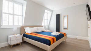 Un dormitorio con cama, mesita de noche y ventana con persianas.