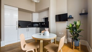 Una cucina moderna con mobili bianchi, un piano di lavoro nero e un tavolo rotondo in legno con due sedie.