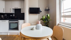 Una cucina moderna con mobili bianchi, un piano di lavoro nero e un tavolo da pranzo rotondo con sedie.
