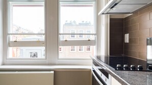 Eine Küche mit großem Fenster, einem Herd und einer gefliesten Spritzschutzleiste.