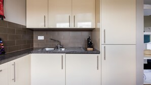 A kitchen with beige cabinets, a granite countertop, a stainless steel sink, and a knife block. - Bright Covent Garden Studio - Netflix & Nespresso (London)