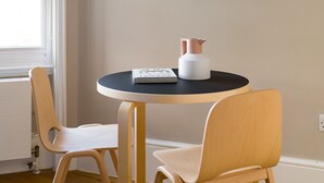 A round table with a book and a white bottle with a rose gold cap. Two wooden chairs are placed around the table. - Bright Covent Garden Studio - Netflix & Nespresso (London)