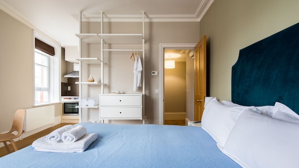 Une chambre d’hôtel avec un lit, une armoire, un bureau et une chaise.