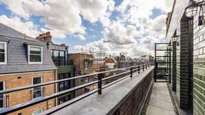 Un bâtiment urbain moderne doté d’une terrasse sur le toit, de murs en briques et surplombant un ciel dégagé.